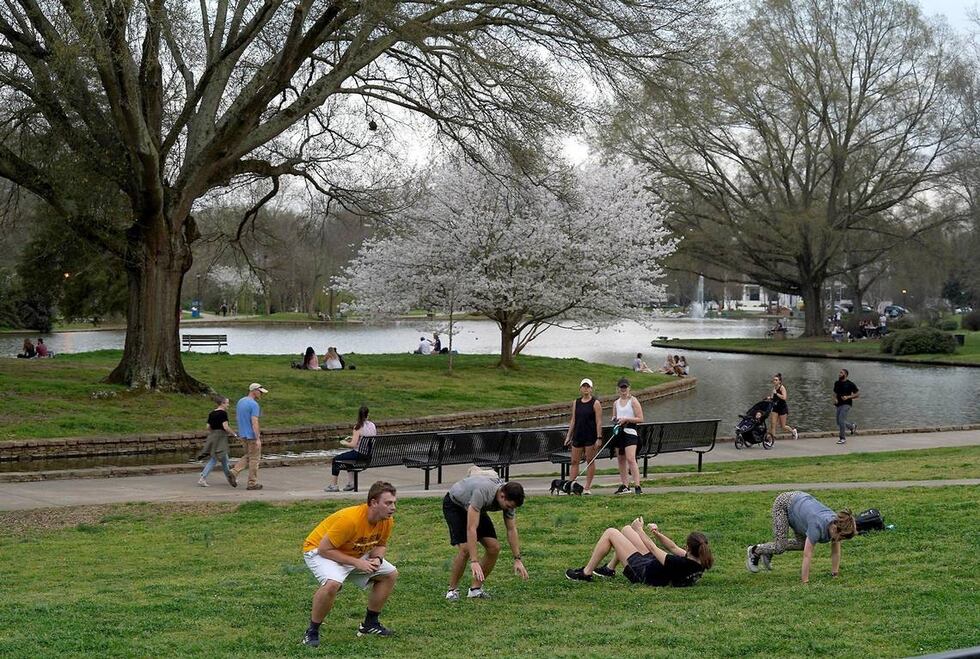 People exercise near the band shell at Freedom Park as others enjoy a walk or run on Thursday,...