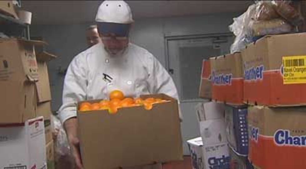 A man holds a box of oranges donated to Wayside Christian Mission by Lynn's Paradise Cafe.